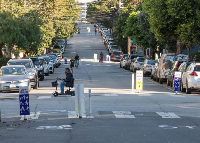 Active slow street with families biking and people walking